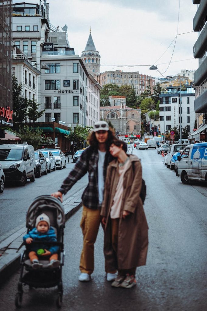 couple-standing-in-the-street-with-a-baby-in-a-stroller-14688740 Urban scene of parents with baby in stroller, iconic city landmark backdrop.