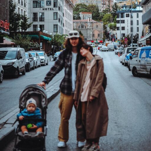 Urban scene of parents with baby in stroller, iconic city landmark backdrop.